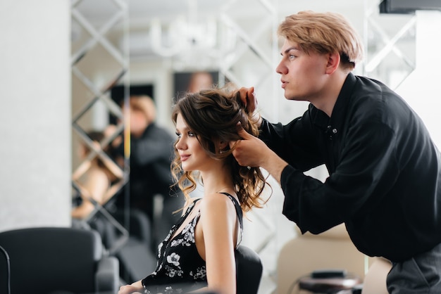 In un bellissimo e moderno salone di bellezza, uno stilista professionista fa un taglio di capelli e un'acconciatura per una ragazza. bellezza e moda.