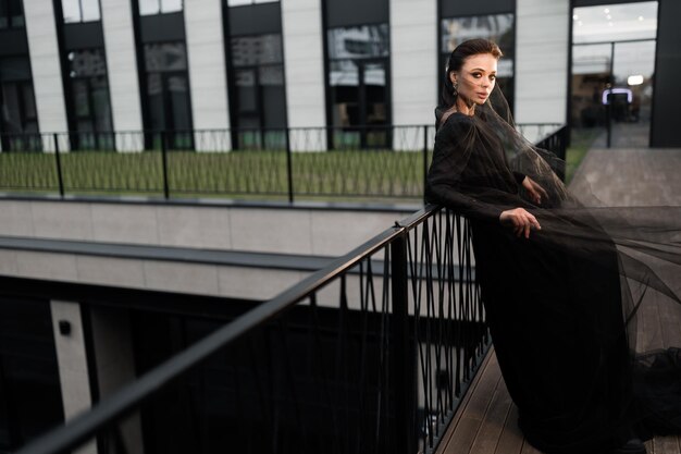 Foto bella sposa moderna che posa per la foto all'esterno in abito nero e velo guardando il lato elegante donna attraente sta lavorando come concetto di moda modello