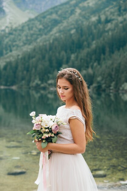 山の湖の近くの美しい現代のカップルは結婚式の写真を作る