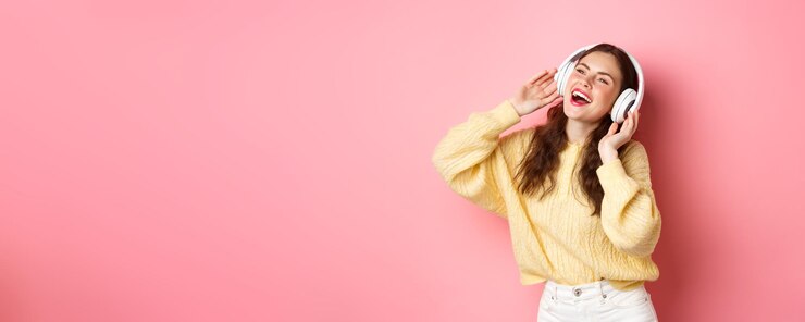 Photo 笑顔とダのワイヤレス ヘッドフォンで音楽を聴いて好きな歌を歌っている美しい現代の女の子