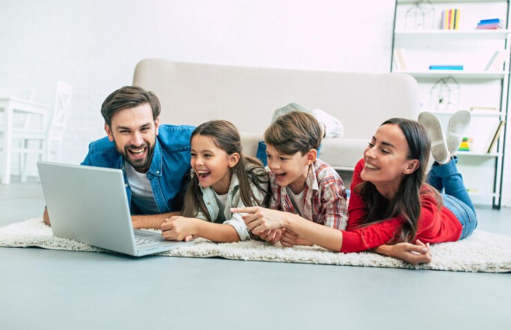 Photo beautiful modern young family lying on the floor at home and doing something in laptop