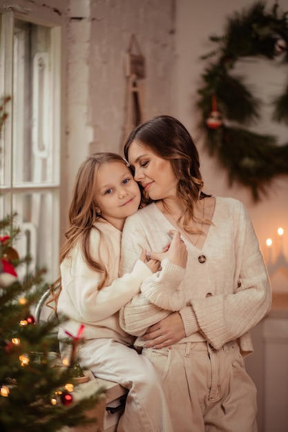 Beautiful mom and daughter near the Christmas tree