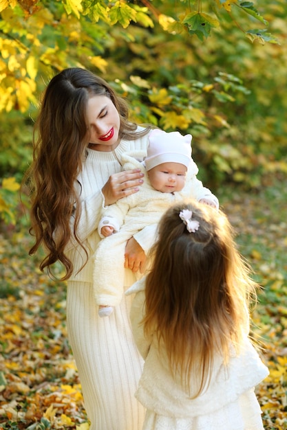 A beautiful mom and her sweet daughters are walking in the autumn park