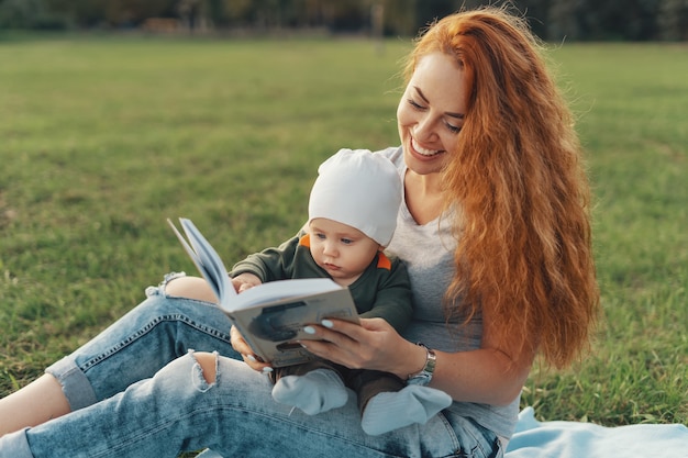 La bella mamma sta leggendo un libro con il suo bambino carino