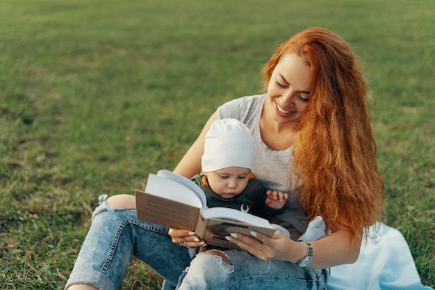 La bella mamma sta leggendo un libro con il suo bambino carino