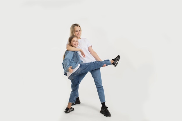 Beautiful mom with her little daughter dancing and having fun on a white isolated background