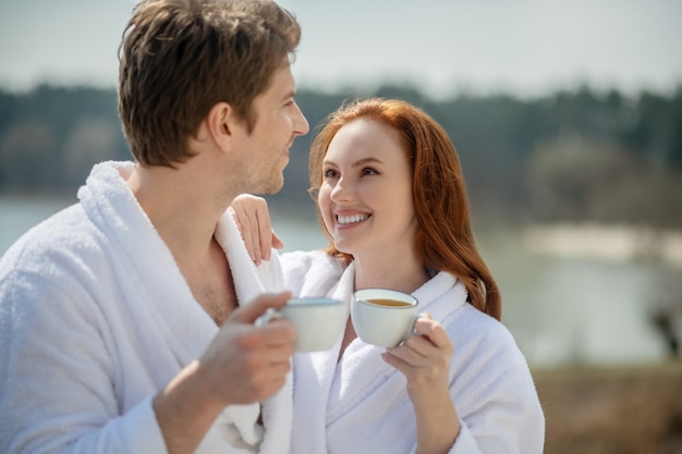 Beautiful morning. Smiling happy man and woman having morning coffee outside