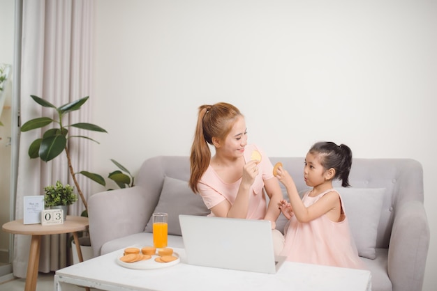 Beautiful mother and child looks at laptop screen spend time in kitchen using app education program