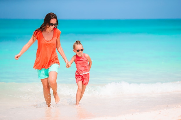 Beautiful mother and daughter at Caribbean beach enjoying summer vacation.