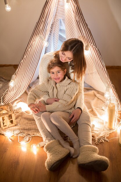 Beautiful mother and daughter Christmas eve sitting in the cosy interior New year