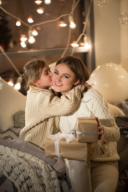 Beautiful mother and daughter opening a magical Christmas gift in the cozy interior of the house. New year.