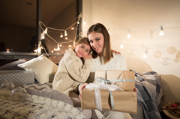 Beautiful mother and daughter opening a magical Christmas gift in the cozy interior of the house