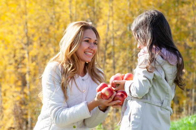 Beautiful mother, daughter play with red apples