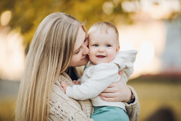 Beautiful mother and daughter walking in the park in autumn portrait Mom and daughter family concept A little girl in her mother's arms