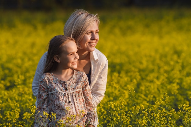 Beautiful mother and daughter on a yellow rape field