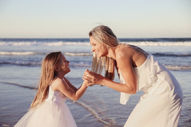 Photo beautiful mother and daugther laughing together on the beach