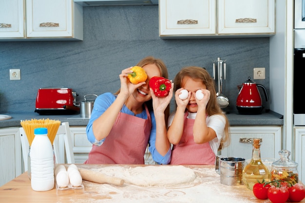 Bella madre e la sua adorabile figlia divertirsi in cucina mentre si cucina il cibo