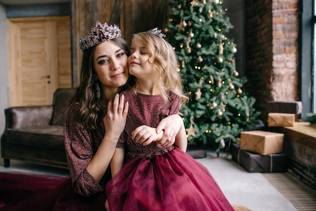 Beautiful mother and her daughter in the image of the queen and the princess in the Marsala-colored dress