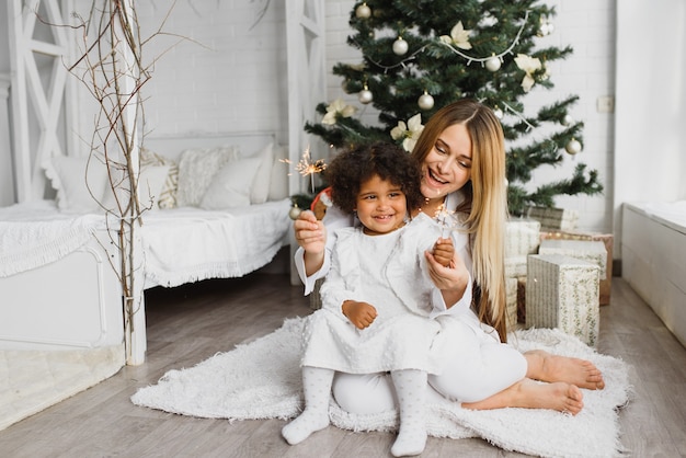 Beautiful mother and her daughter near the Christmas tree