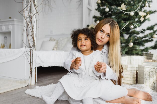 Beautiful mother and her daughter near the Christmas tree