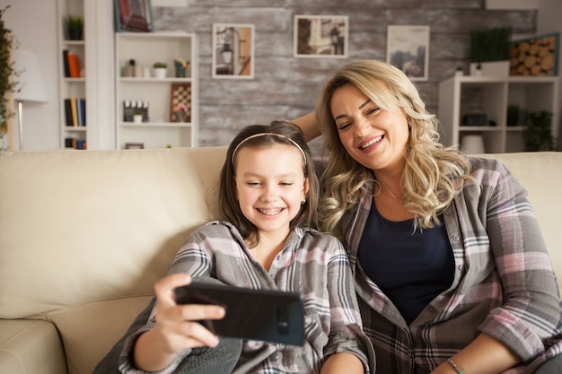 beautiful mother and her daughter with braces watching something funny on smartphone.