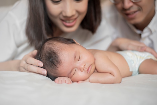 Beautiful mother is playing with her newborn baby in the bedroom.