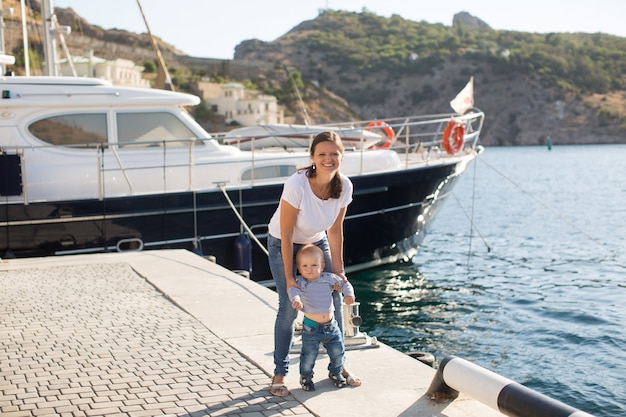 beautiful mother is walking on the pier with her little baby boy son with first steps