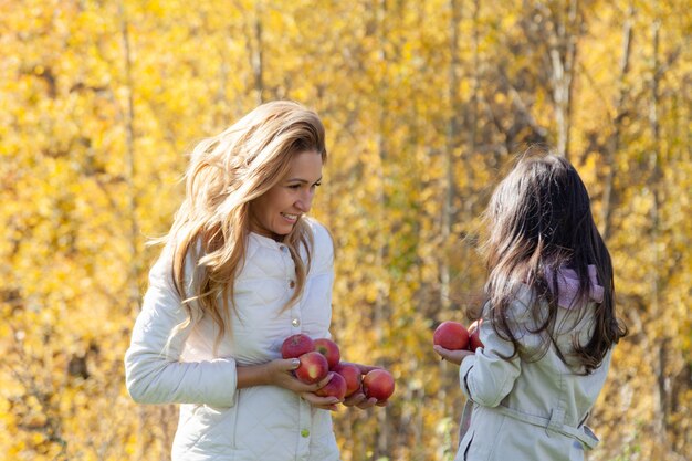 Photo beautiful mother and little daughter play with ripe red apples