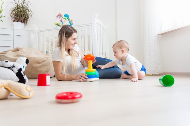 Beautiful mother playing with her baby boy on floor