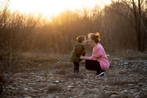 Foto bella madre che gioca con suo figlio in natura contro il tramonto concetto di giorno delle madri