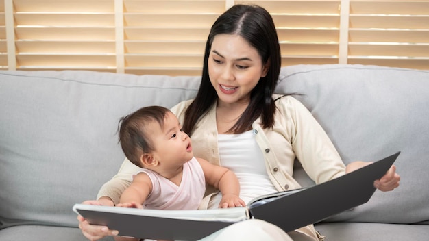 家で女の赤ちゃんに本を読んで美しい母親