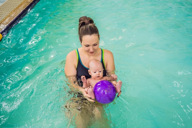 Beautiful mother teaching cute baby girl how to swim in a swimming pool Child having fun in water with mom