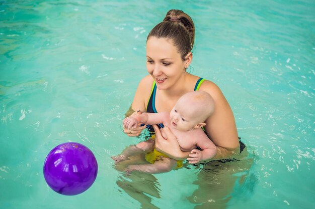 Beautiful mother teaching cute baby girl how to swim in a swimming pool Child having fun in water with mom