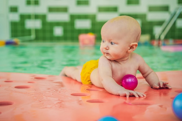 Beautiful mother teaching cute baby girl how to swim in a swimming pool child having fun in water with mom