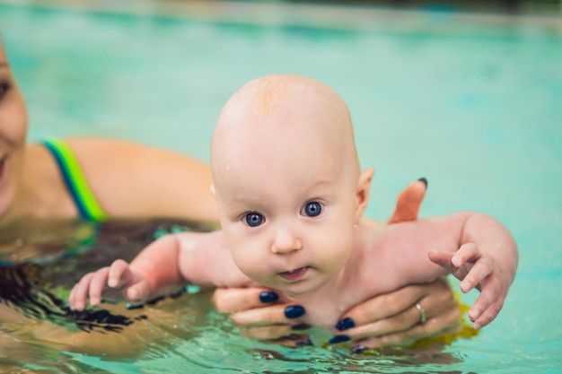 Foto bella madre che insegna a una bambina carina a nuotare in una piscina bambino che si diverte in acqua con la mamma