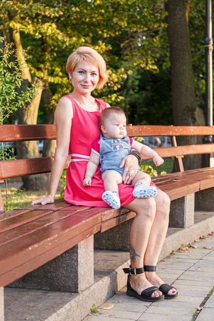 Beautiful mother with her daughter and son are sitting on a bench in the park in the summer