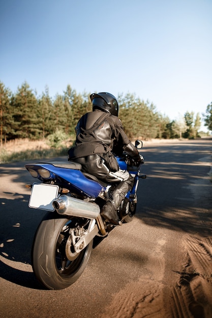 林道を走る美しいバイク。夕日の暖かい太陽光線の中でバイクに乗って空の道を運転して楽しんでください。