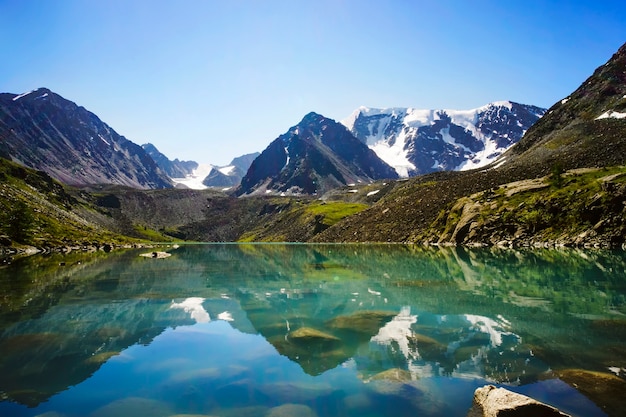 Beautiful mountain lake with turquoise clear water in the Altai Republic Siberia Russia. reflection of mountains with snow-capped peaks in crystal clear water.