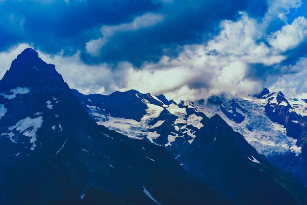 Beautiful mountain landscape in summertime Mighty mountains with snow in cloudy weather