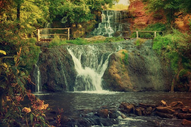 Beautiful mountain rainforest waterfall with fast flowing water and rocks, long exposure. Natural seasonal travel outdoor background in hipster vintage style