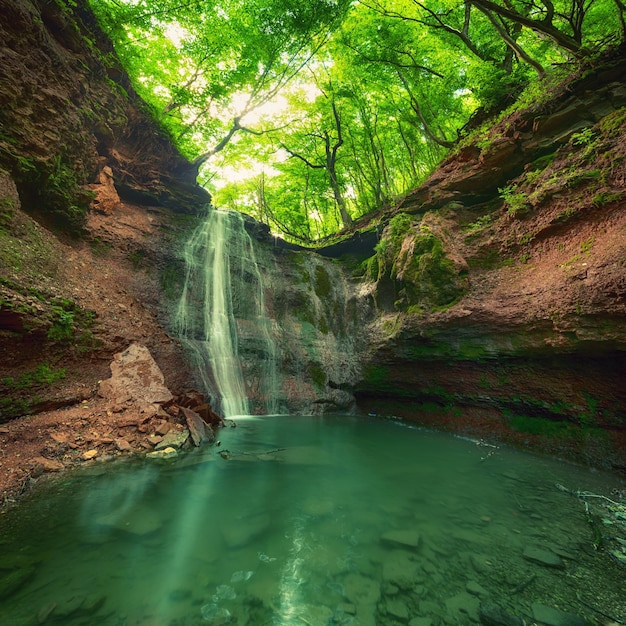 Beautiful mountain rainforest waterfall with fast flowing water and rocks long exposure Natural seasonal travel outdoor background in hipster vintage style