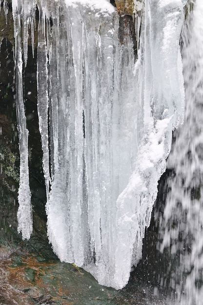 Фото Красивый горный водопад, покрытый льдом. зимний пейзаж. замерзший ручей в горах