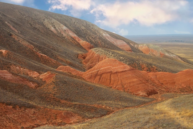 Foto bellissimo terreno montuoso paesaggio steppico con erba secca montagne rosse e cielo blu