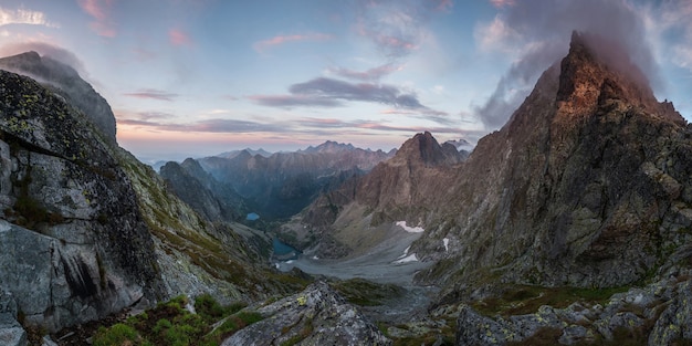 Beautiful mountains at sunset with pink clouds and a lake in the valley, landscape