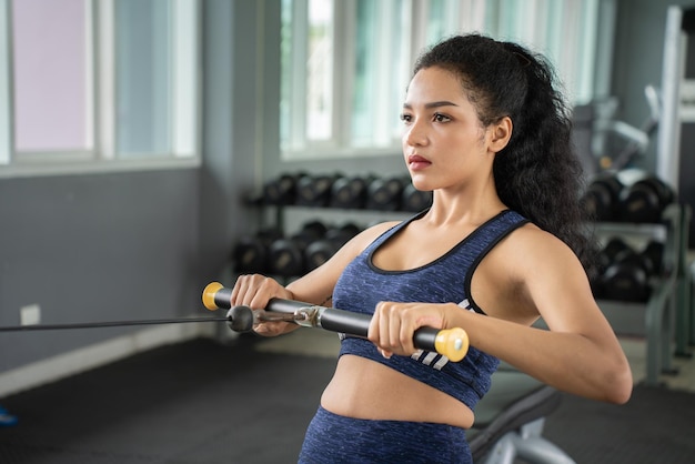 Beautiful muscular fit woman exercising building muscles Muscular athletic female bodybuilder pulled on sports simulator