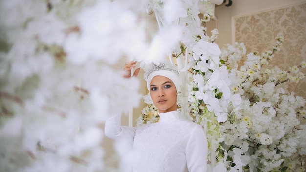 Foto bella sposa musulmana in abito da sposa bianco e copricapo da sposa