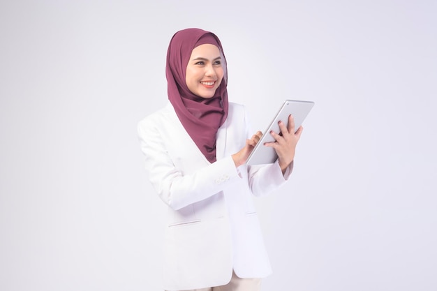 Bella donna d'affari musulmana che indossa un abito bianco con tablet hijab in studiox9