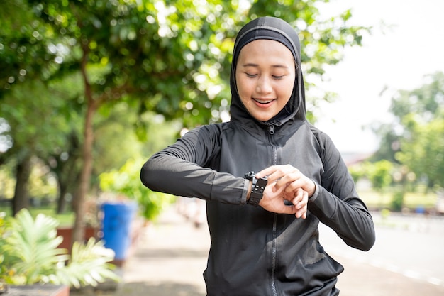 Красивая мусульманская женщина отслеживает частоту сердечных сокращений на умных часах во время тренировки на открытом воздухе