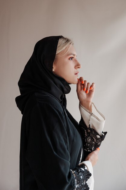 Beautiful muslim woman in traditional arabian abaya dress on gray background