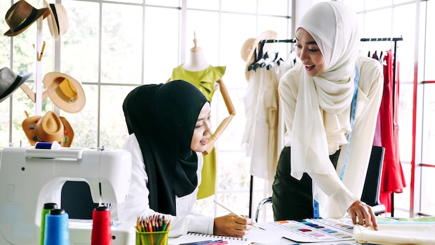 Belle donne musulmane che disegnano insieme la siluetta dei vestiti all'ufficio.